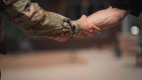 military man and civilian grabbing arms shaking hands close up slow motion