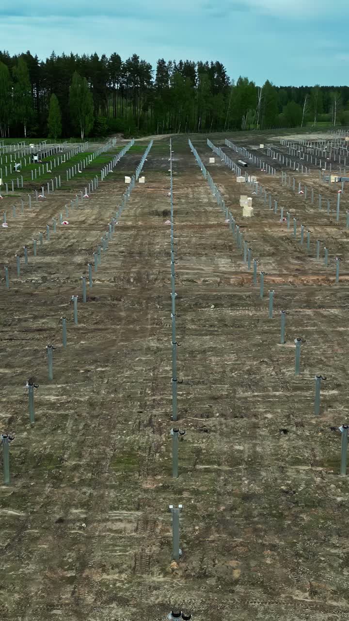 Cleared dirt field shows support posts installed for new solar panel array, aerial