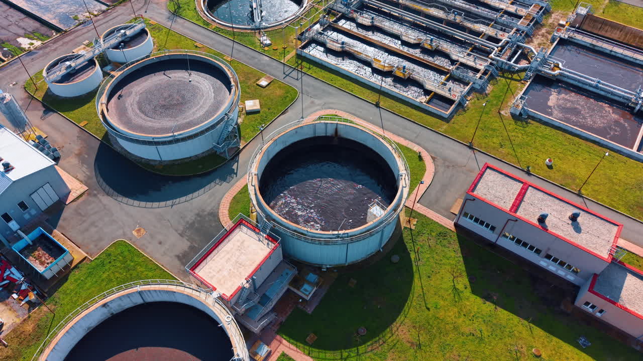 Aerial perspective of industrial water treatment tanks and buildings. Overhead shot of circular and rectangular tanks with red roofed service structures