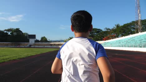 back view of boy running at stadium