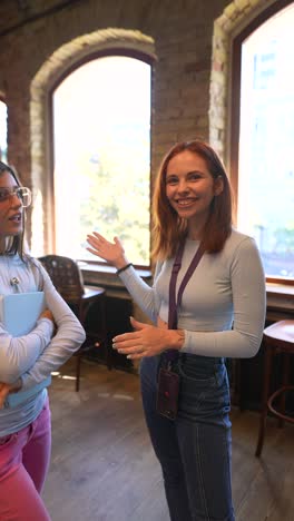 dos mujeres jóvenes discutiendo en un café o biblioteca