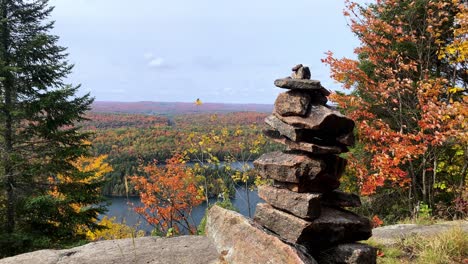 Handgefertigtes-Steinmonument-Mit-Blick-Auf-Einen-See-Und-Orangefarbene,-Rote,-Grüne-Und-Gelbe-Blätter