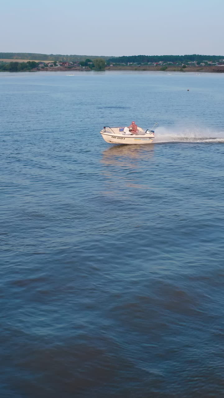Kyiv, Ukraine, 2 May 2025: Aerial view of speed boat on river. Aerial drone view of motor boating through river. Vertical video