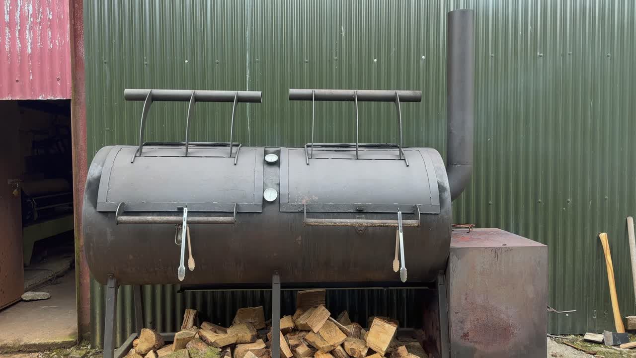 거대한 강철 바베큐는 공공 행사를 위해 밖에서 음식을 그릴 때 연기를 피운다.