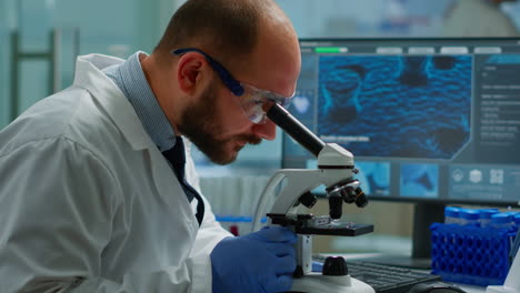 científico masculino mirando bajo el microscopio en un laboratorio de desarrollo médico