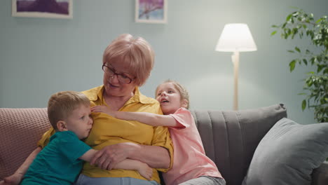 adorable little children hug grandmother in living room