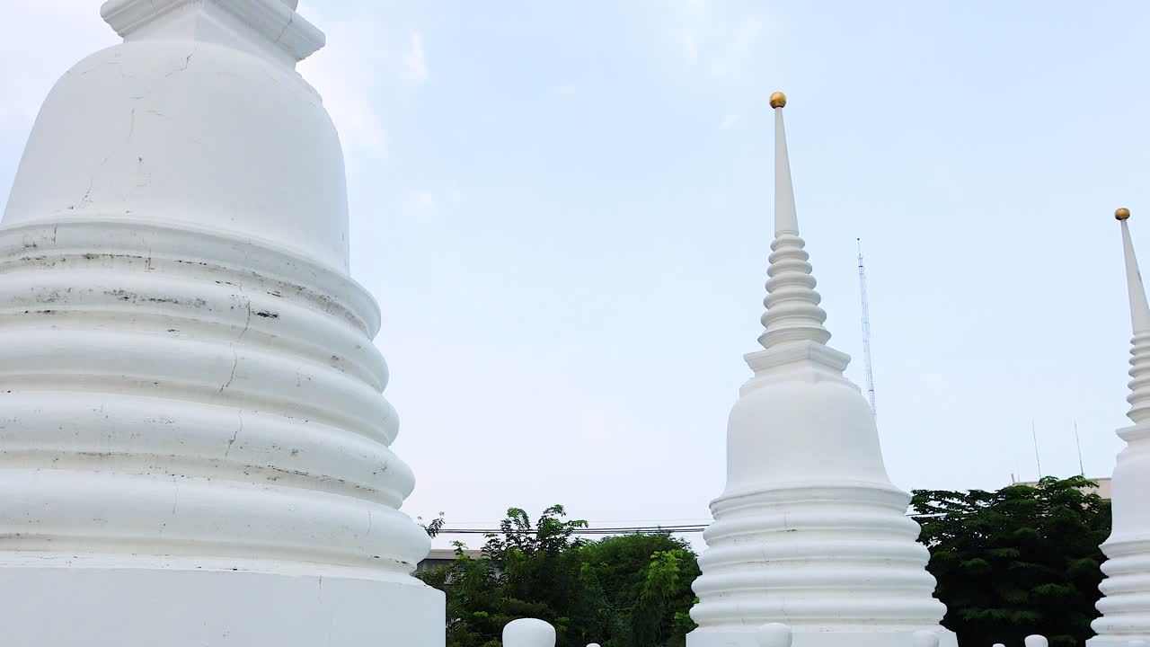 Un video sereno che mostra le pagode bianche di Wat Prayurawongsawat a Bangkok, con movimenti di camera fluidi e una luce diurna soffusa.