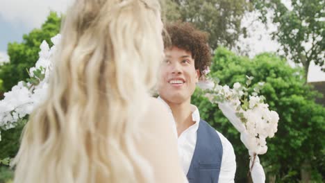 happy diverse couple dancing in garden on sunny day at wedding