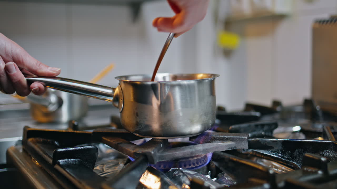 Hands stirring sauce spoon in kitchen cooker closeup. Unknown woman chef cooking