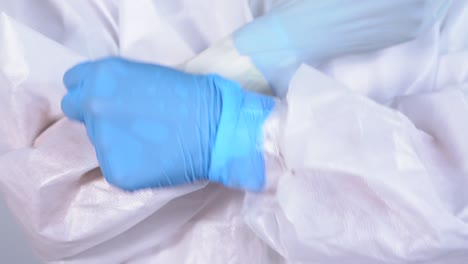 nurse in protective ppe suit putting on gloves to attend to a patient