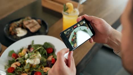 primer plano de la pantalla del teléfono inteligente tomando fotografías de los platos en la mesa