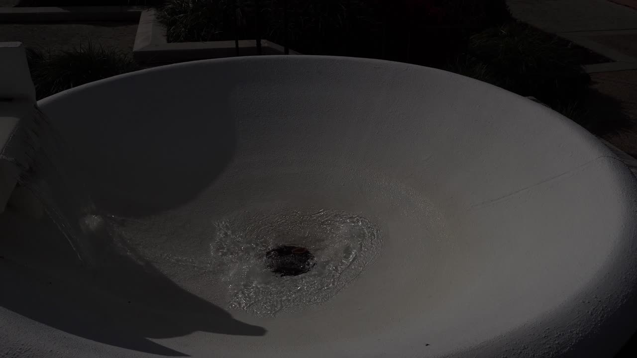 Una fontana circolare bianca dove l'acqua viene proiettata verso l'alto attraverso un'apertura centrale