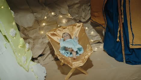 baby jesus figurine in golden manger surrounded by lights, nativity scene