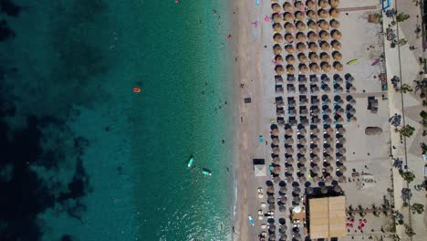 Sauberer-Strand-An-Der-Küste-Von-Albanien-Im-Mittelmeer-Mit-Sonnenschirmen-In-Der-Nähe-Von-Smaragdgrünem-Meerwasser