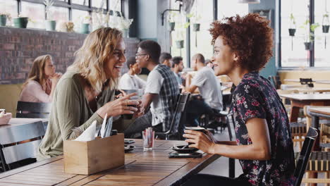 dos amigas se reúnen en una mesa en una cafetería y hablan