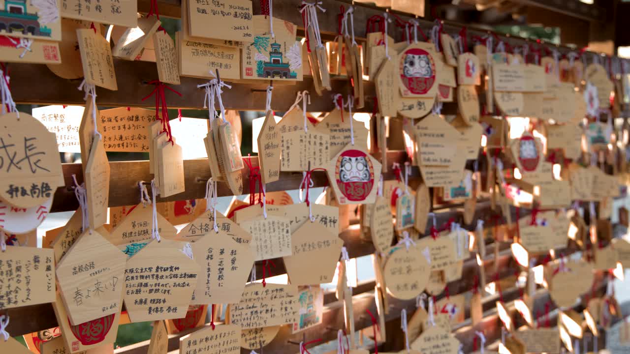 日本の神道神社に掛けられた多数の木製の絵馬のクローズアップパンショット。