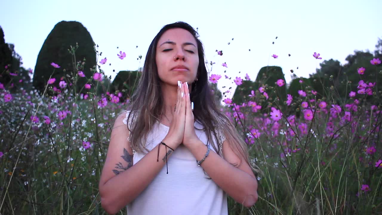 joven latina respirando en calma en medio de un hermoso campo púrpura con flores de hojalata