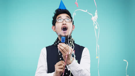 crazy face asian man pulling party popper slow motion photo booth blue background