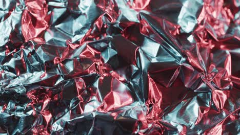 Close-up-of-silver-and-red-crumpled-pieces-of-plastic-material-in-slow-motion