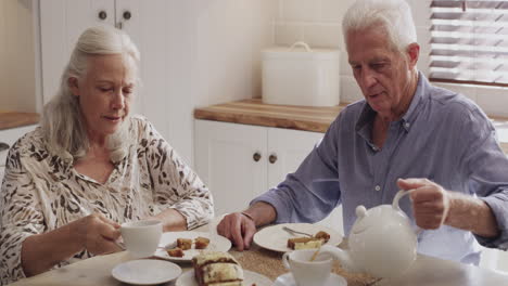 a senior couple enjoying tea and cake at home