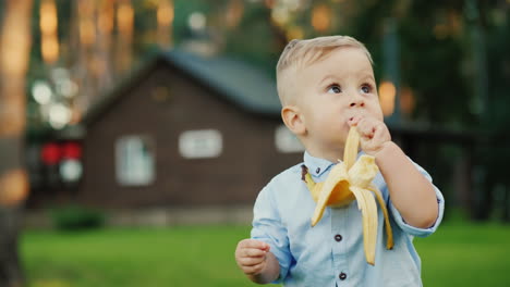 funny kid raises a banana from the ground and takes it in his mouth