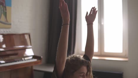 woman in sportswear is meditating in lotus position sitting on yoga mat with closed eyes at home, hands in namaste