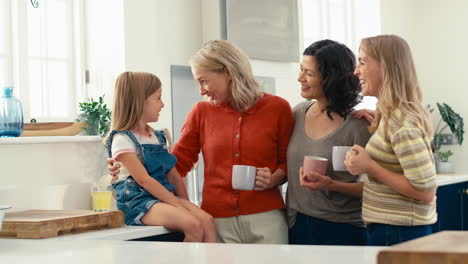 familia femenina de varias generaciones con pareja del mismo sexo sentada en la cocina en casa hablando