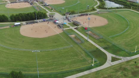 hoverina aerial view of suburban community ball park complex with softball games in progress