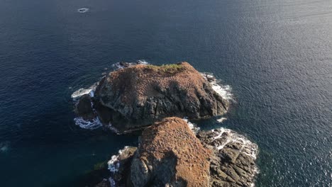 drone video over a small rocky islands with waves crushing