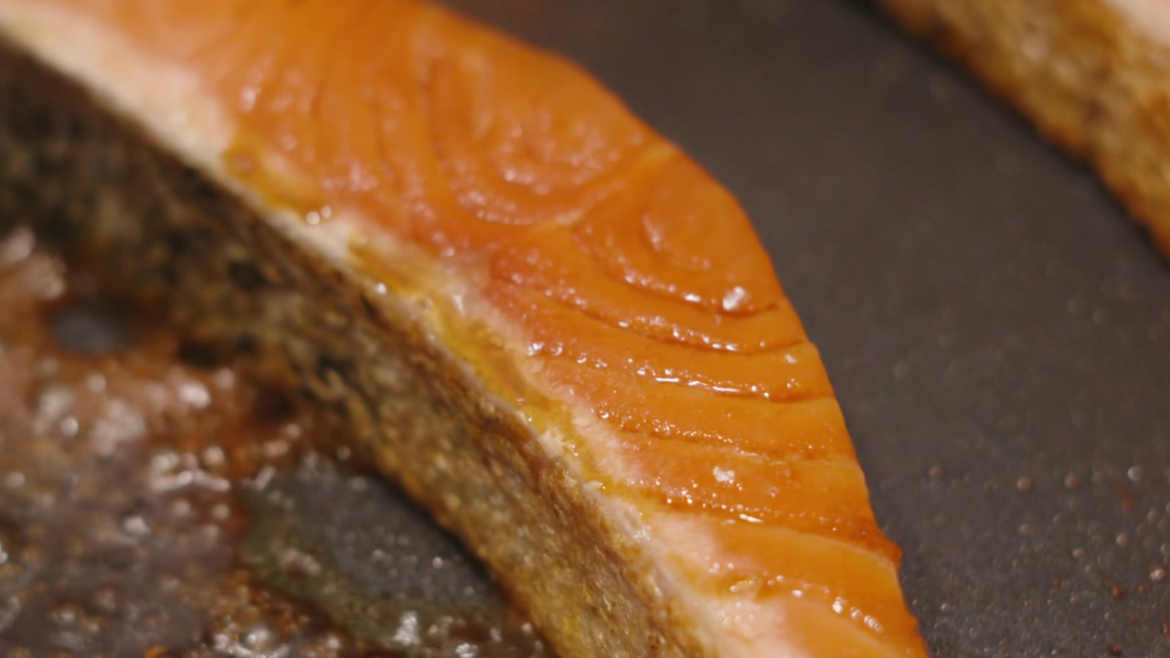 Primo piano di salmone con pelle croccante che cuoce con salsa di soia che bolle