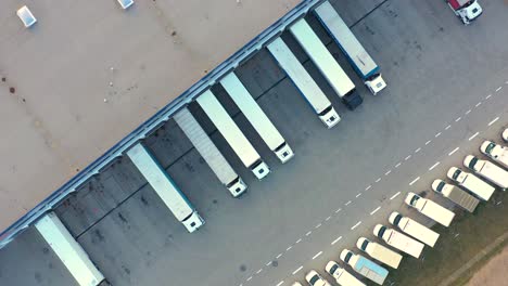 vista aerea di un semirimorchio con rimorchi merci in piedi sulle rampe dei magazzini per il carico e lo scarico delle merci nel grande parco logistico con mozzo di carico