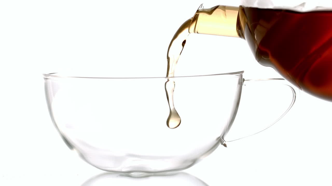 Hot tea pouring into glass cup