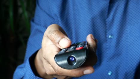 persona que sostiene un control remoto de la televisión