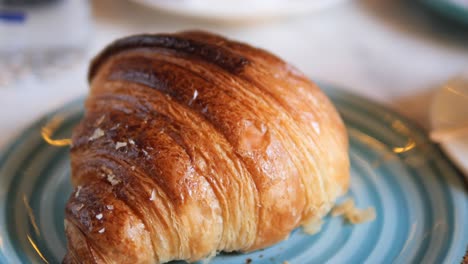 primer plano de un croissant recién horneado en un plato azul