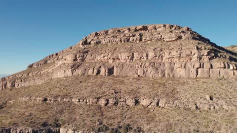 Drone-aerial-fly-by-of-a-large-cliff-face-with-layers-of-rock-and-washout