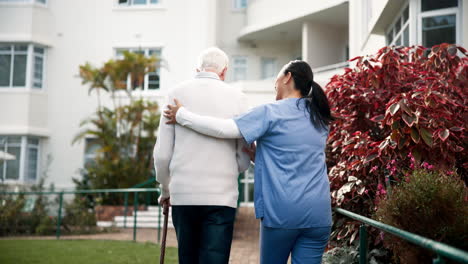 nurse assisting elderly man in nursing home garden