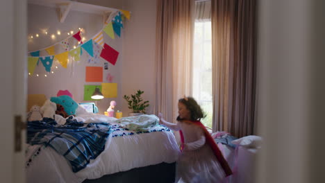 niña feliz saltando en la cama vistiendo disfraz jugando a un juego disfrutando de la imaginación juguetona en un dormitorio colorido en casa