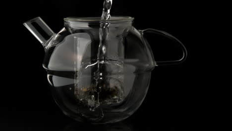 water pouring into glass teapot over loose tea