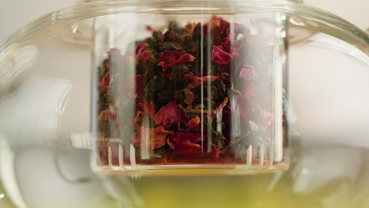 Tè aromatico ai petali di rosa in infusione in una teiera di vetro