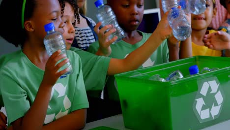 escolares poniendo botellas en contenedores de reciclaje en el escritorio en el aula 4k