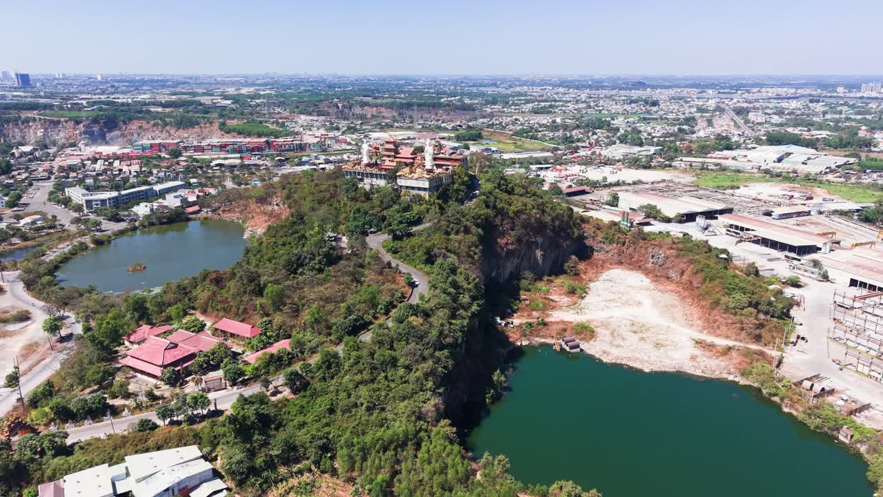 Vista aérea das colinas e lagos perto de uma cidade durante o dia, com edifícios ao longe e estradas sinuosas pela paisagem.