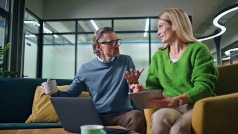 Successful-colleagues-talking-at-lounge-zone.-Corporate-couple-working-together