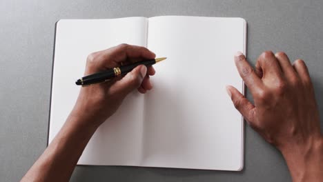 close up of hand writing with pen on book with copy space on gray background in slow motion