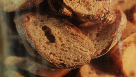 slices of artesian bread in glass pot on bakery shop close-up. bread with black poppy garnish on top and white flour on top. artisan bread is making by skill bakers using natural and high-quality ingredients. food with health and flavour benefits.