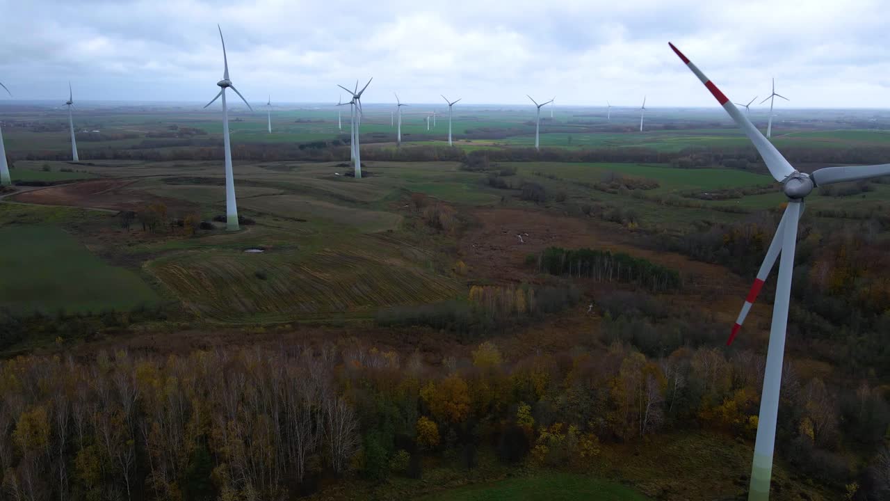 Aerial shot of a group rotating wind turbines in a wind farm for renewable electric power production in the countryside on a cloudy day