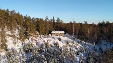 cabaña de madera noruega tradicional en el bosque de invierno - toma aérea de drones