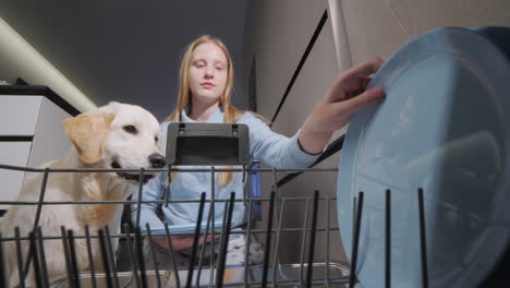 girl and dog loading dishwasher