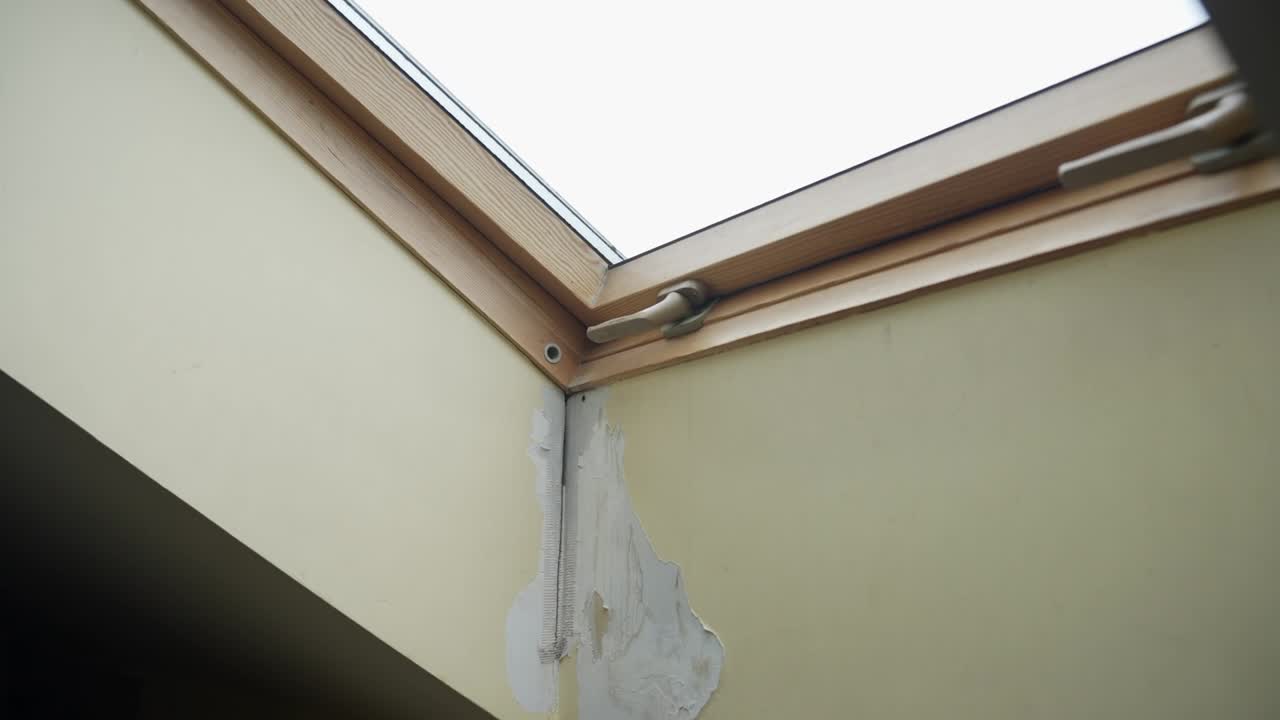 Pioggia che filtra da un lucernario in una casa durante una tempesta