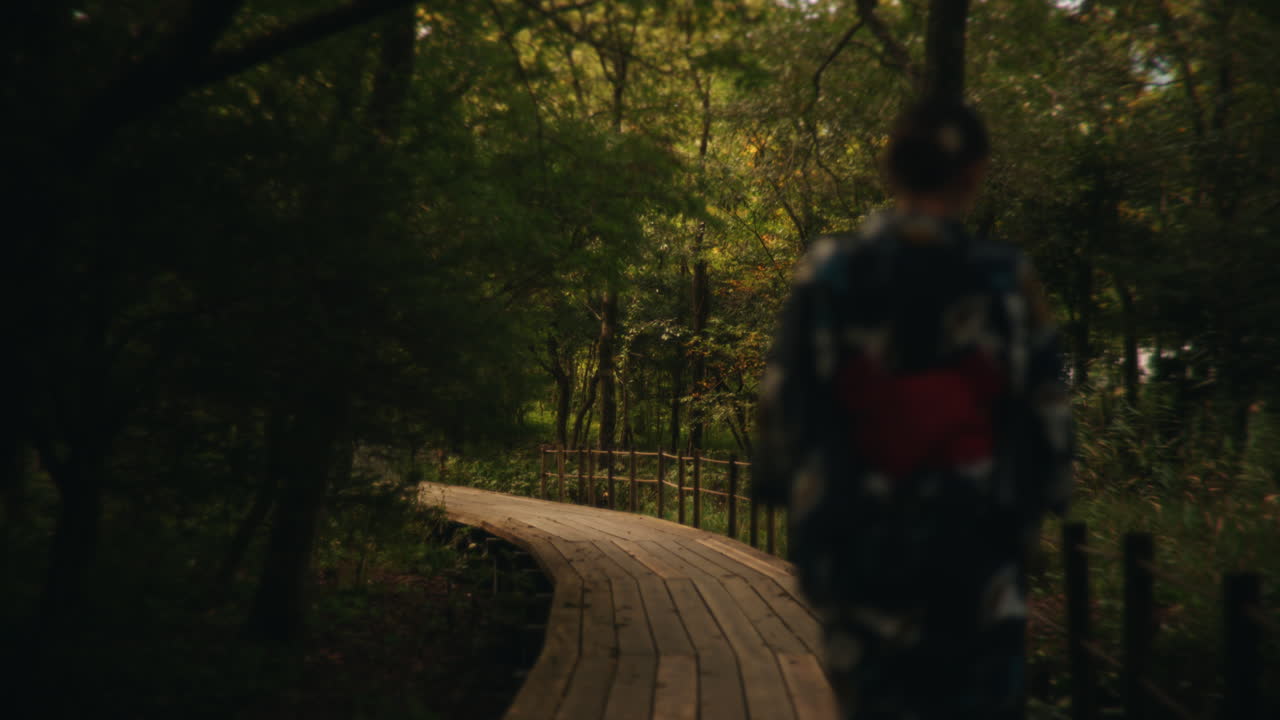 A woman walks on a wooden path in a forest