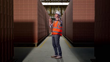 full body side view of asian male engineer with safety helmet screaming goal celebrating working with red brick packed in stacks are stored